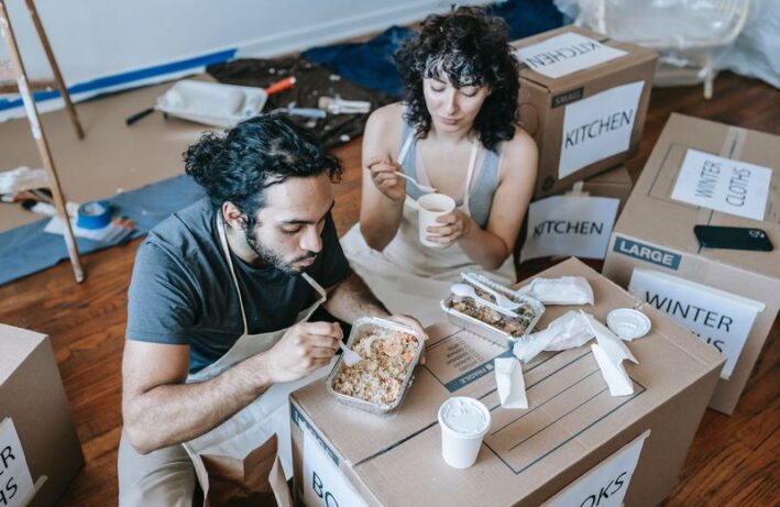 kobieta i mężczyzna jedzą posiłek na kartonach - opakowania ekologiczne
